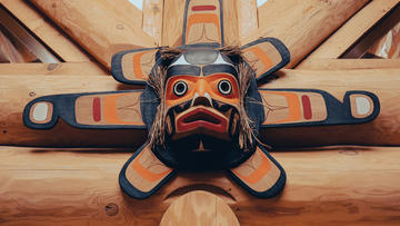 Indigenous carving of an animal head in black, red, and orange.